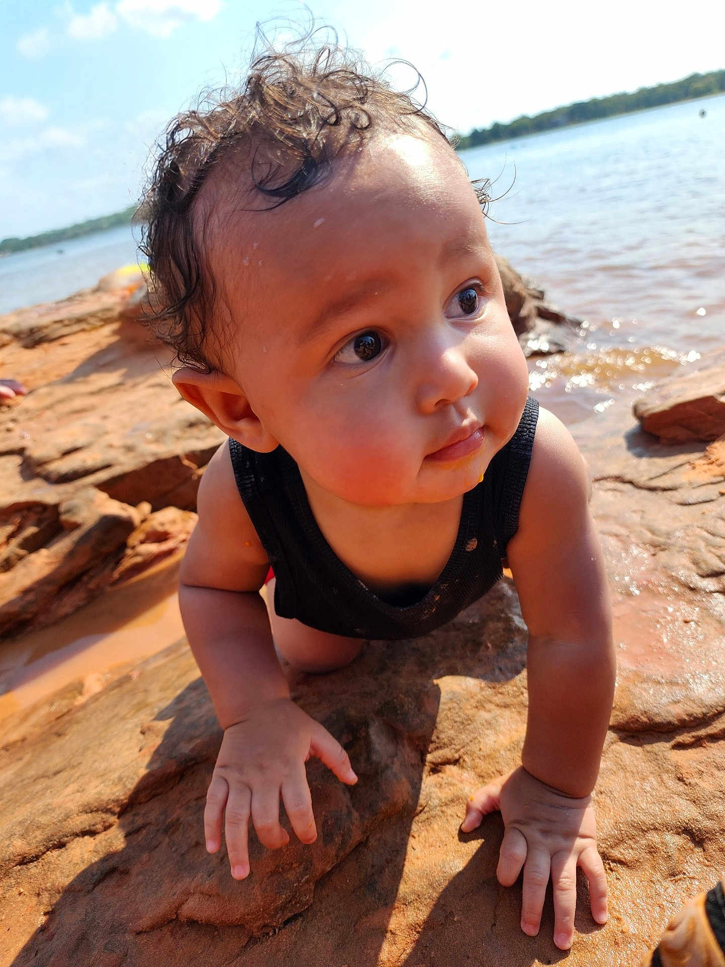 Isa joined the competition — help win amazing prizes! baby, child, curly_hair, wet_hair, rock, water, outdoor, crawling, sunlight, nature, riverbank, face, hands, tank_top, skin, portrait, summer, exploration, expression, closeup