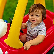 Evilynn is registered to the contest to win money with this photo: baby, casual, child, cute, daylight, grass, greenery, hand, happy, outdoor, playtime, portrait, red, seat, short_sleeve_shirt, smiling, toddler, toy_car, yellow, young_child