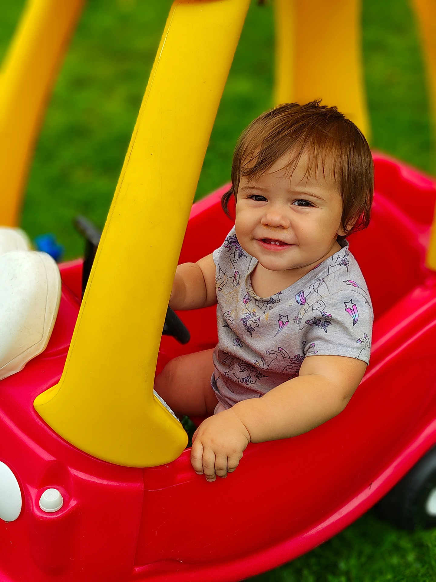 Evilynn is registered to the contest to win money with this photo: baby, casual, child, cute, daylight, grass, greenery, hand, happy, outdoor, playtime, portrait, red, seat, short_sleeve_shirt, smiling, toddler, toy_car, yellow, young_child
