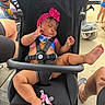 baby, infant, sleeping, stroller, pink_headband, flower, bracelet, jewelry, harness, outdoor, sunlight, family, vacation, shopping, wheelchair, sandals, toys, pacifier, portrait, relaxed