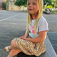 Miya a rejoint le concours — aidez-le/la à gagner de superbes lots ! child, girl, blonde_hair, tshirt, skirt, leopard_print, sandals, sitting, outdoor, bench, stone, smiling, daylight, trees, building, casual, happy, young, portrait, park