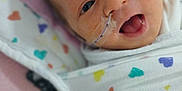Hazleigh is registered to the contest to win money with this photo: baby, infant, face, feeding_tube, blanket, swaddled, heart_pattern, hospital, medical_tape, newborn, cute, lying_down, close_up, soft_texture, pink, colorful, awake, mouth_open, eyes, toddler