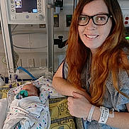Hazleigh is registered to the contest to win money with this photo: woman, infant, baby, hospital, medical_equipment, blanket, glasses, smile, bed, patient, healthcare, pacifier, gown, monitor, person, care, nurse, mother, newborn, indoor