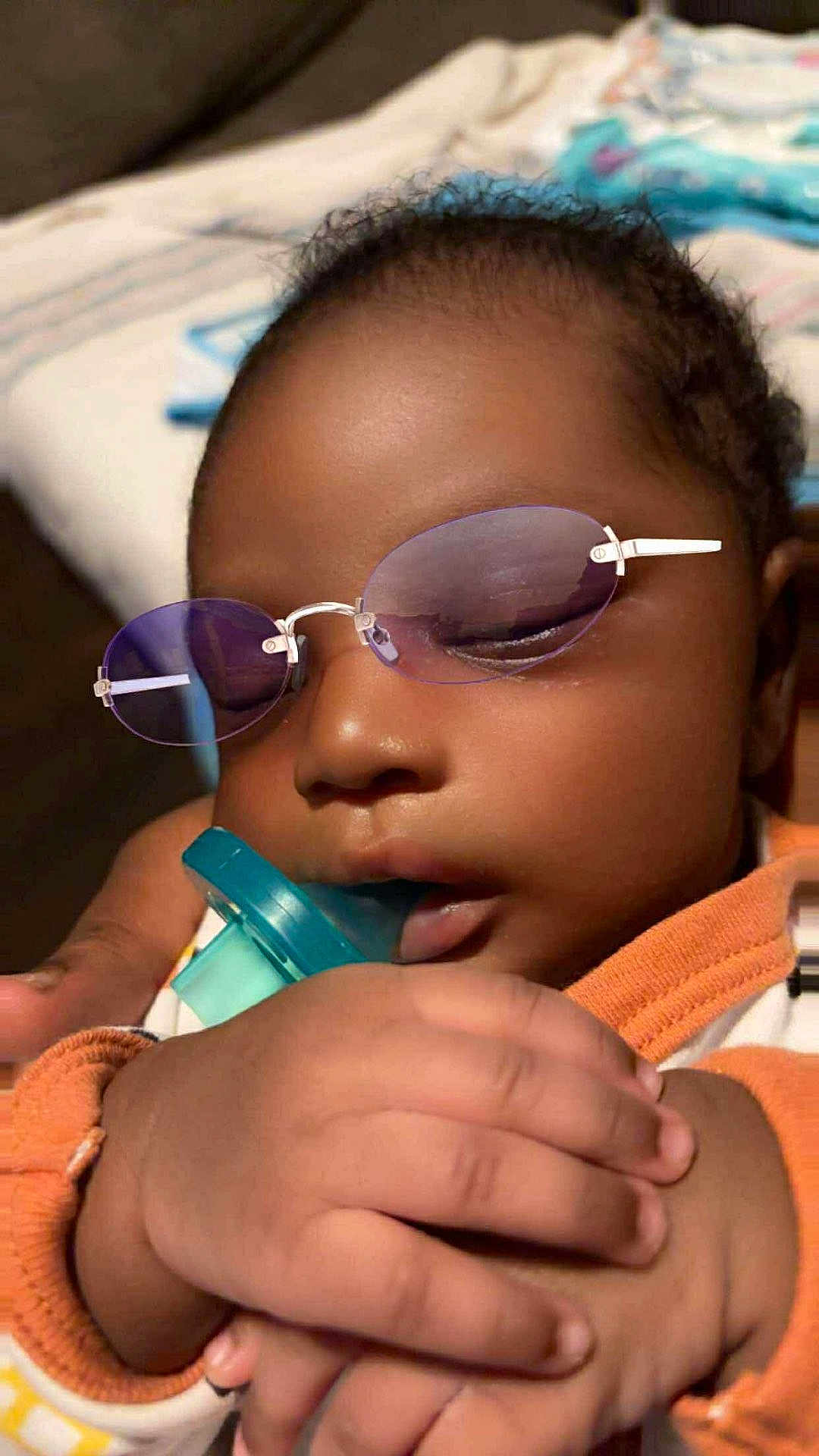 Yosohn is registered to the contest to win money with this photo: baby, infant, pacifier, glasses, purple_glasses, hand, sleeping, closeup, face, skin, clothing, orange, white, indoor, child, person, cute, peaceful, newborn, portrait