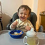 toddler, child, high_chair, smile, laugh, food, french_fries, bowl, sippy_cup, drink, indoor, happy, cute, clothing, person, meal, table, hair, face, seat