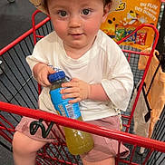 Lyam a rejoint le concours — aidez-le/la à gagner de superbes lots ! toddler, child, shopping_cart, hat, straw_hat, juice_bottle, shorts, white_shirt, indoors, supermarket, cute, curious, sitting, red_cart, baby, person, floor, retail, grocery, casual