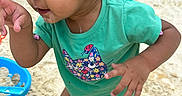 Nevaeh joined the competition — help win amazing prizes! toddler, child, baby, portrait, outdoor, playground, sand, summer, turquoise_shirt, floral_shirt_design, curly_hair, brown_eyes, smiling, curious, standing, barefoot, adult_hand, playground_toy, backyard, daylight