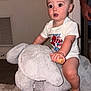 baby, child, indoor, plush_toy, rocking_elephant, carpet, hand, tattoo, wooden_handle, shirt, expression, face, foot, furniture, person, room, wall, floor, toy, candid