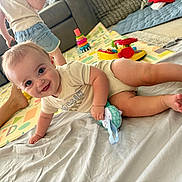 Grayson is registered to the contest to win money with this photo: baby, child, toy, crawling, smiling, indoor, blanket, playmat, sofa, denim_shorts, person, floor, happy, cute, home, toddler, legs, hand, play, living_room