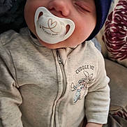 Dax is registered to the contest to win money with this photo: baby, sleeping, pacifier, hat, clothing, zipper, blanket, couch, pillow, floral, hand, face, infant, cute, cozy, indoors, child, peaceful, resting, wearing