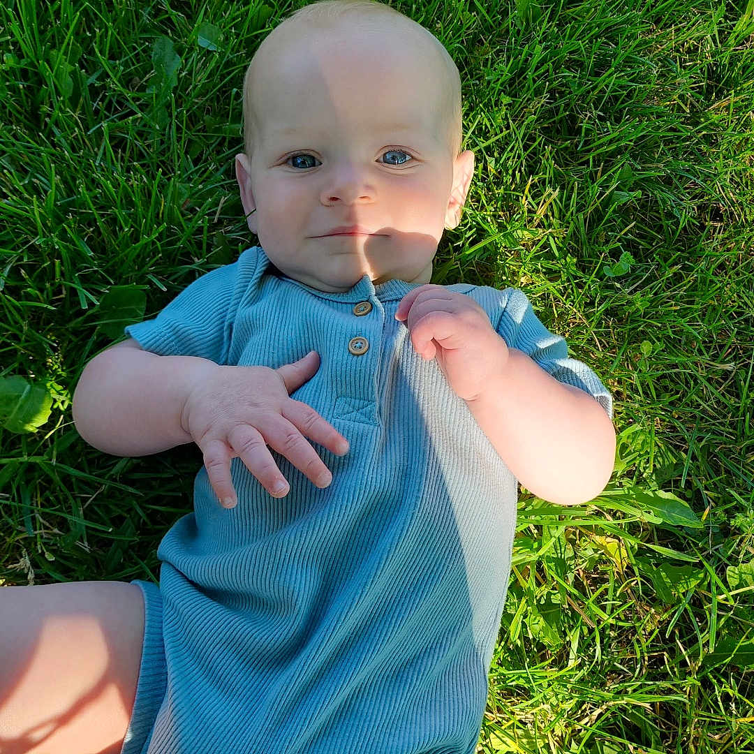 Rykir joined the competition — help win amazing prizes! baby, child, grass, outdoor, blue_clothing, romper, sunlight, shadow, face, hand, legs, nature, greenery, person, infant, summer, casual, cute, portrait, lying_down