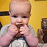 baby, child, high_chair, food, eating, hands, face, blue_eyes, expression, yellow_wall, indoor, meal_time, messy, cute, infant, clothing, seat_belt, portrait, young_child, home