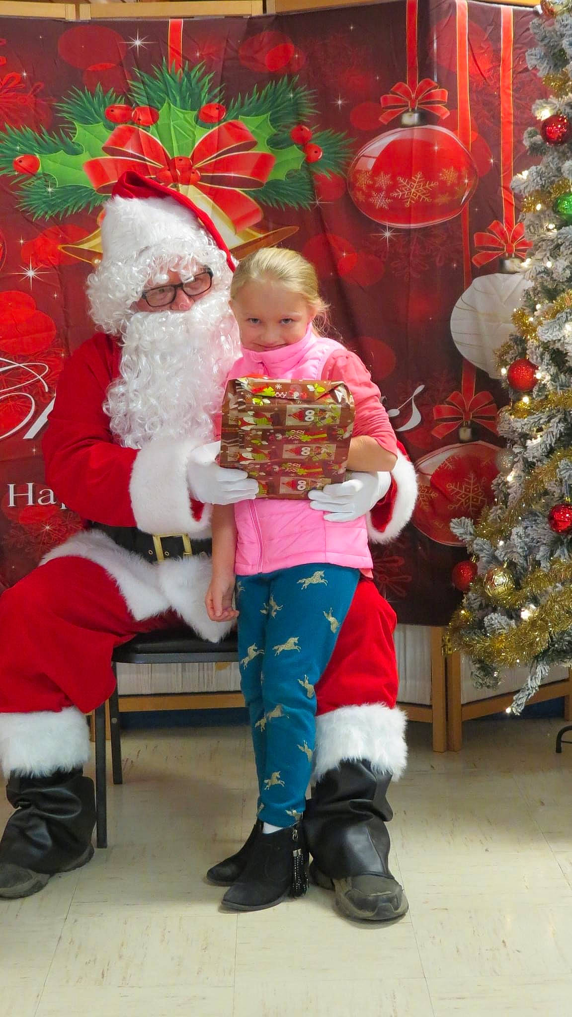 Miranda is registered to the contest to win money with this photo: boot, child, christmas, christmas_decoration, christmas_eve, christmas_ornament, christmas_tree, conifer, event, fictional_character, happy, holiday, holiday_ornament, interior_design, lap, ornament, person, red, santa_claus, toddler