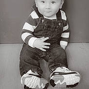 Thaïrhonn a rejoint le concours — aidez-le/la à gagner de superbes lots ! baby, child, sitting, striped_sweater, denim_overalls, shoes, floor, portrait, smile, indoor, cute, young_child, monochrome, casual_clothing, hand_gesture, face, person, young, happy, small