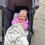 baby, stroller, blanket, pink_clothing, turban, smiling, happy, child, outdoor, pavement, black_stroller, cozy, wrapped, infant, cute, person, seat, graco_brand, warm, portrait