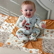 Declan is registered to the contest to win money with this photo: arms, baby, bed, blanket, child, clothing, crib, cute, face, happy, headboard, indoors, infant, joyful, pajamas, person, quilt, sitting, smiling, young_child