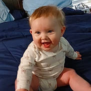 Declan joined the competition — help win amazing prizes! baby, child, smiling, sitting, bed, pillow, blanket, hand, onesie, indoor, window, blinds, furniture, happy, person, skin, head, hair, room, holding