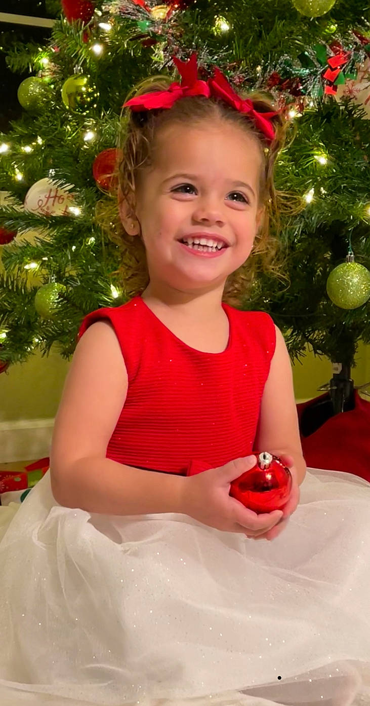 Harper Rose is registered to the contest to win money with this photo: beauty, christmas_decoration, christmas_ornament, christmas_tree, dress, event, facial_expression, fun, happy, head, holiday, holiday_ornament, human_body, joy, person, pink, plant, red, smile, standing