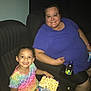 child, adult, popcorn, drink, movie_theater, seat, glasses, smile, colorful_clothing, purple_shirt, happy, indoor, food, snack, person, leisure, family, together, entertainment, fun