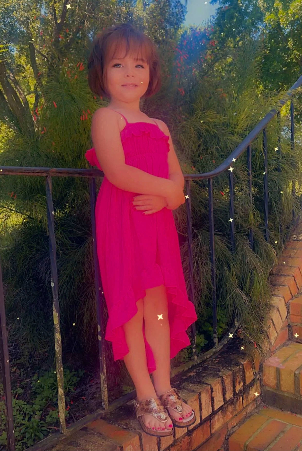 Haiden joined the competition — help win amazing prizes! baby_toddler_clothing, dress, face, fence, grass, happy, leaf, leg, leisure, magenta, people_in_nature, person, pink, plant, sandal, sleeve, standing, thigh, toddler, tree