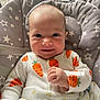 Daisy joined the competition — help win amazing prizes! baby, smiling, infant, onesie, carrot_pattern, cushion, star_pattern, seated, happy, face, child, indoor, cute, clothing, person, skin, head, hand, expression, comfort