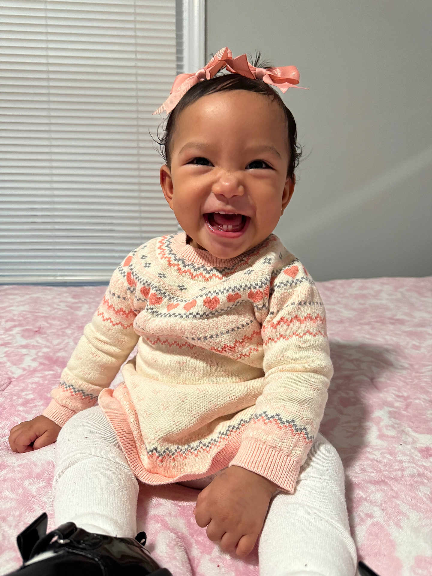 Alessia Alanna is registered to the contest to win money with this photo: baby, child, smiling, sitting, sweater, bow, pink, white_tights, black_shoes, indoors, blanket, cute, happy, portrait, face, hands, headband, patterned_clothing, infant, cozy