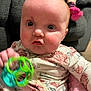baby, infant, baby_face, floral_onesie, toy, green_toy, rattle, closeup, portrait, indoor, sofa, pink_blanket, rosy_cheeks, big_eyes, red_hair, chubby_cheeks, hand, motion_blur, sitting, casual_clothing