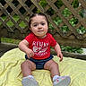 toddler, child, baby, sitting, outdoor, blanket, red_shirt, denim_shorts, pigtails, cute, wooden_lattice, greenery, curious, portrait, footwear, white_socks, casual_clothing, daylight, nature, expression