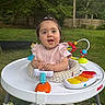 Mary is registered to the contest to win money with this photo: baby, child, walker, toy, outdoor, grass, greenery, playtime, smiling, happy, infant, cute, person, young_child, fence, nature, daylight, colorful, portrait, lawn