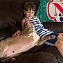 Odin joined the competition — help win amazing prizes! child, boy, dog, couch, indoor, relaxing, pet, companion, striped_clothing, brown, comfort, casual, blanket, home, furniture, resting, happy, animal, friendship, portrait
