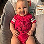 Lyla is registered to the contest to win money with this photo: baby, infant, smiling, onesie, pink_clothing, baby_seat, face, hands, legs, indoor, happy, child, cute, cushion, person, portrait, home, seat, sitting, bright