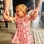 Freya participe au concours pour gagner de l'argent avec cette photo : adult, barefoot, child, dress, floor, furniture, hair_tie, hands, home, indoor, joy, person, pink, rug, smile, strawberry_pattern, support, tattoos, toddler, walking