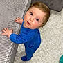 Tiago a rejoint le concours — aidez-le/la à gagner de superbes lots ! baby, blue_clothing, carpet, child, couch, curious, cute, floor, furniture, gray_couch, hands, home, indoor, infant, looking_up, onesie, person, soft_lighting, standing, white_carpet