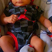 Zion joined the competition — help win amazing prizes! baby, infant, red_hat, black_clothing, socks, plush_toy, blanket, lying_down, indoors, cute, child, person, newborn, soft_toy, casual_wear, comfortable, resting, small_hands, small_feet, cozy