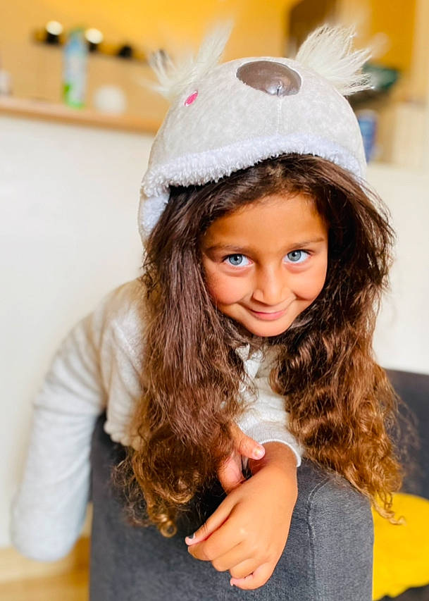 Lina participe au concours pour gagner de l'argent avec cette photo : cap, child, clothing, costume_hat, ear, eyebrow, eyelash, face, fashion_design, hairstyle, happy, hat, headpiece, helmet, joy, long_hair, outerwear, person, skin, sleeve