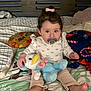 Maialen is registered to the contest to win money with this photo: toddler, child, pacifier, plush_toy, bed, blanket, pillow, cookie_pillow, blue_duck, pink_bow, clothing, long_sleeve, pants, bare_feet, indoor, cute, sitting, portrait, face, toy
