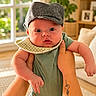 baby, child, hat, bib, hands, tattoo, indoor, window, plant, furniture, couch, home, portrait, cute, infant, person, green_clothing, natural_light, face, expression