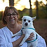 animal, casual, daylight, dog, forest, glasses, happy, holding, leash, nature, outdoor, person, pet, portrait, small_dog, smile, sunset, trees, white_clothing, woman