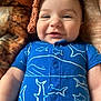 baby, blanket, blue_onesie, child, closeup, comfortable, cozy, cute, face, happy, indoors, infant, lying_down, portrait, shark_print, skin, smiling, soft_texture, warm_colors, whale_print