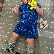 Colton is registered to the contest to win money with this photo: 3_months, arrow_pattern, baby, blue_clothing, child, crib, face, grey_bedding, hands, indoor, infant, legs, lying_down, milestone_marker, orthopedic_shoes, romper, smiling, socks, toy, yellow_toy