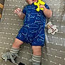 3_months, arrow_pattern, baby, blue_clothing, child, crib, face, grey_bedding, hands, indoor, infant, legs, lying_down, milestone_marker, orthopedic_shoes, romper, smiling, socks, toy, yellow_toy