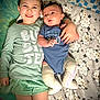 child, baby, siblings, smiling, blanket, onesie, long_sleeve_shirt, cast, leg_cast, bed, lying_down, happy, family, indoor, cute, person, face, infant, toddler, text_on_clothing