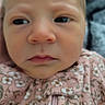 baby, infant, child, face, portrait, close_up, serious, expression, eyes, nose, mouth, floral, pink_clothing, outfit, zipper, indoor, person, head, photography, cute