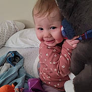 Anastasia joined the competition — help win amazing prizes! baby, child, infant, smiling, face, portrait, stuffed_animal, gray_toy, bed, bedroom, blanket, pajamas, floral_clothing, toys, baby_bottle, cuddling, indoor, cozy, happy, family_snapshot