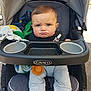 baby, child, stroller, grumpy, blanket, clothing, face, person, outdoor, footwear, socks, seat, toy, expression, head, cushion, human, infant, transportation, winter_clothes