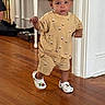 Bryce is registered to the contest to win money with this photo: toddler, child, indoor, curly_hair, walking, clothing, shorts, shirt, crocs, footwear, wooden_floor, home, person, cute, playful, sailboat_pattern, expression, young_child, casual, floor