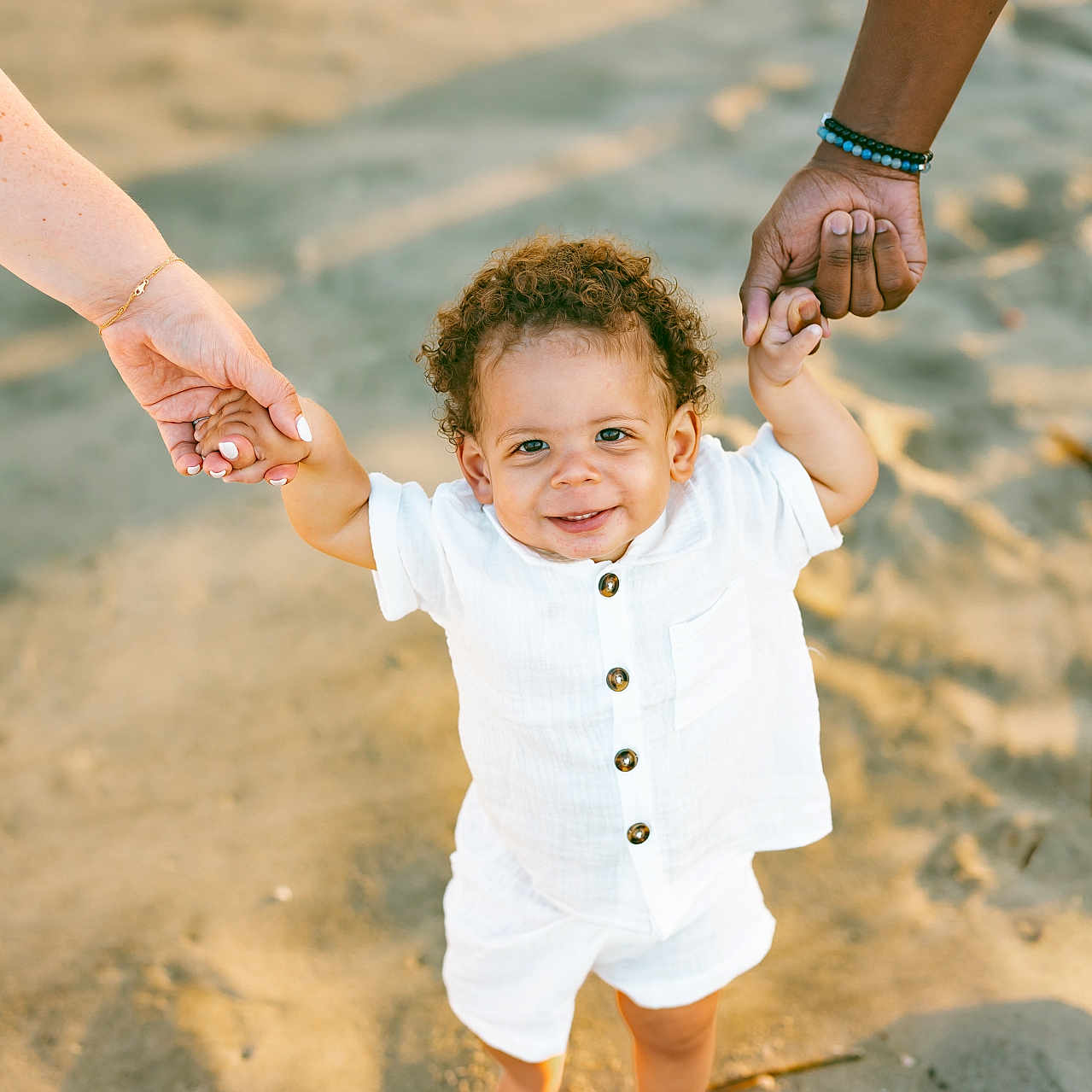 Bryce joined the competition — help win amazing prizes! toddler, child, sand, beach, barefoot, white_clothing, smiling, holding_hands, adult_hands, outdoor, sunlight, happy, curly_hair, portrait, people, summer, vacation, family, walking, casual