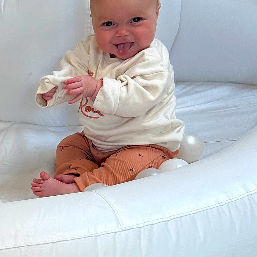 Lotte-Rose joined the competition — help win amazing prizes! baby, barefoot, child, cozy_clothes, cute, floor_mat, happy, indoor, infant, light_skin, playful, portrait, short_hair, sitting, small_hands, smiling, tongue_out, toy_balls, warm_lighting, white_chair