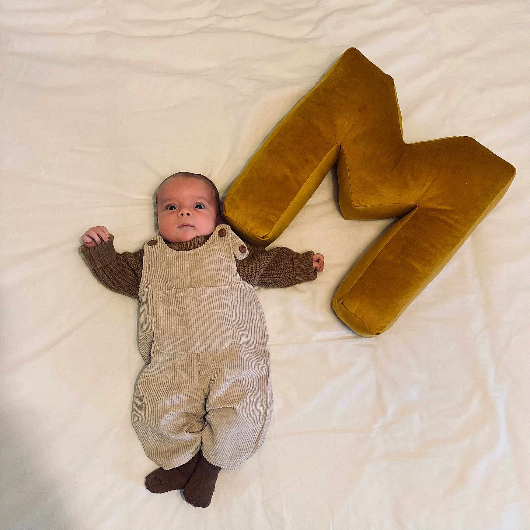 Marso participe au concours pour gagner de l'argent avec cette photo : baby, blanket, brown_clothing, button, child, cozy, cute, fabric, face, head, indoor, infant, letter_m, lying_down, overalls, plush, portrait, small_hands, socks, soft_texture