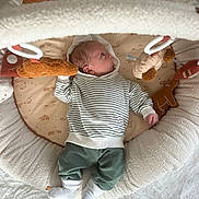 Marso a rejoint le concours — aidez-le/la à gagner de superbes lots ! baby, infant, child, striped_hoodie, green_pants, white_socks, baby_nest, plush_toys, soft_toys, cozy, comfortable, curious, lying_down, indoors, cute, newborn, face, looking_up, childhood, resting